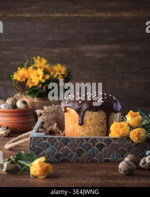 Das Osterkulich, ein traditionelles Süßbrot, steht im Mittelpunkt dieses charmanten Stilllebens, präsentiert in einem rustikalen hellblauen Holztablett. Die Größe, Stockfoto