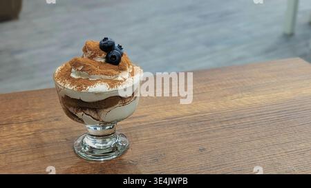 Eine köstliche Nahaufnahme eines klassischen Tiramisu, serviert in einer Glasschale. Das Dessert besteht aus reichhaltigen Schichten Mascarponescreme und kaffeespezialem Ladyfin Stockfoto