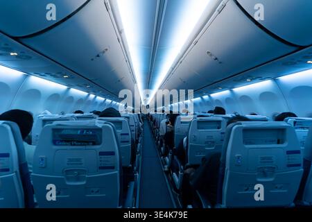 Singapur - 9. Dezember 2025: Blick auf den Innenraum der Economy Class mit Sitzplätzen, sichtbarem Gang und blauer Umgebungsbeleuchtung in einer Boeing 737. Stockfoto