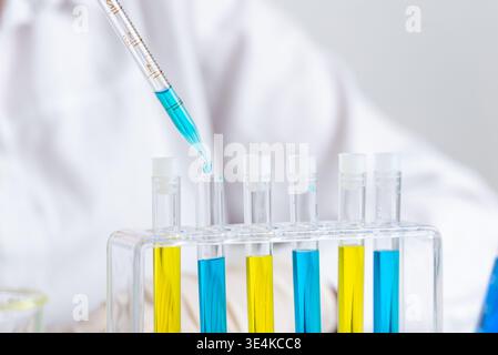 Nahaufnahme der Pipette, die blaue Flüssigkeit in das Reagenzglas tropft, chemisches Experiment und Labortestkonzept mit präziser Messung Stockfoto