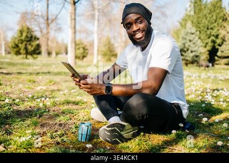Mann in Sportbekleidung, der im Park ein Tablet hält Stockfoto
