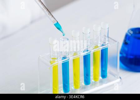 Genaue Details der Pipette, die blaue Flüssigkeit in Reagenzgläser, Laborversuche und chemische Tests mit kontrollierter Präzision abgibt Stockfoto