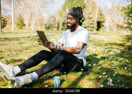 Mann in Sportbekleidung, der im Park ein Tablet hält Stockfoto
