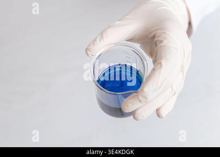 Nahaufnahme des Handbechers mit blauer chemischer Flüssigkeit, Laborversuch und wissenschaftliche Tests Stockfoto