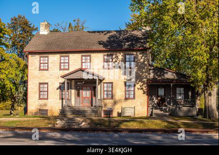 Historisches Brisbois House in Prairie du Chien, Wisconsin, umgeben von Laub im frühen Herbst mit Bäumen, die noch bunte Herbstblätter tragen. Stockfoto