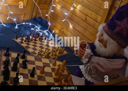 Eine gemütliche und magische Weihnachtsszene mit einer großen dekorativen Puppe in Lila und weiß. Der Hintergrund ist mit leuchtend weißen Feen-LIG verziert Stockfoto