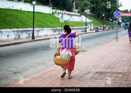Traditioneller Straßenverkäufer mit Körben in Luang Prabang, Laos. Authentische lokale Lifestyle-Szene, die Kultur und Alltagsgeschäft in Southe widerspiegelt Stockfoto