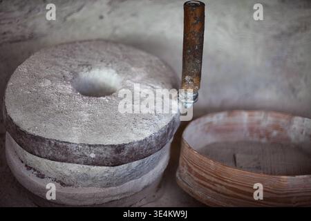 Eine detaillierte Aufnahme mit einem alten manuellen Steinmühle mit Holzgriff, der zum Mahlen von Getreide zu Mehl verwendet wird. Daneben befindet sich ein traditioneller Roun Stockfoto