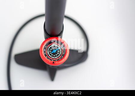 Nahaufnahme eines runden Manometers an einer Bodenpumpe, mit verschwommenem Pumpensockel auf hellem Hintergrund. Stockfoto