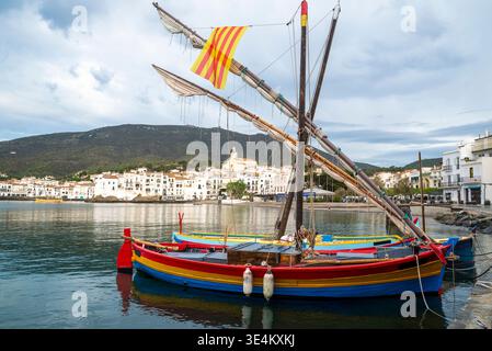 Traditionelle farbenfrohe Fischerboote, die im Hafen mit Küstenlandschaft von Cadaques, Girona, Katalonien, Spanien liegen Stockfoto