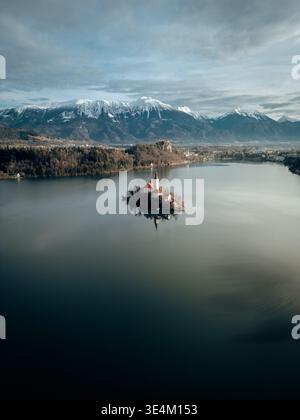 Weite Luftlandschaft des Bleder Sees, Sloweniens, der Inselkirche und der Julischen Alpen im sanften Morgenlicht Stockfoto
