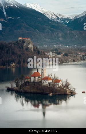 Blick auf den Bleder See aus der Vogelperspektive, Slowenien, Winterlandschaft mit Kirche und umgebendem Wald Stockfoto