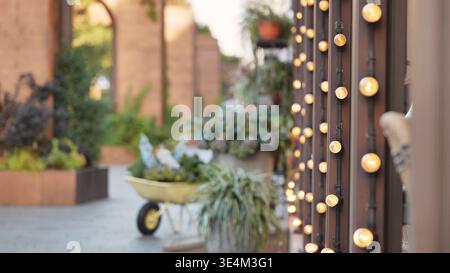 Warme leuchtende Lichterketten in einer rustikalen Gartenterrasse mit weichem Hintergrund Stockfoto