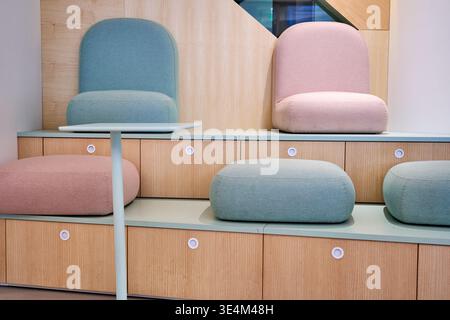 Moderne Bürolounge oder Wartebereich mit eingebautem hellen Eichenschrank mit runden, weißen Griffen, die auf zwei Ebenen angeordnet sind Stockfoto