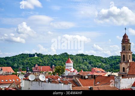 Panoramablick auf die Altstadt von Vilnius mit rot gekachelten Dächern historischer Gebäude im Vordergrund, mit mehreren Kirchtürmen und religiösen Elementen Stockfoto
