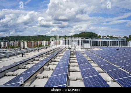 Reihen blauer Photovoltaik-Solarpaneele auf einem flachen gewerblichen Dach mit Betonballast-Montagesystemen. Die Installationsfunktionen Stockfoto