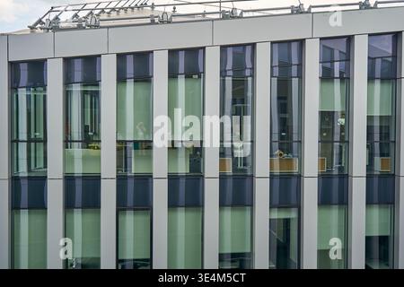 Nahaufnahme einer modernen Bürogebäudefassade mit einem sich wiederholenden Rastermuster aus vertikalen weißen Struktursäulen im Wechsel mit Stockfoto