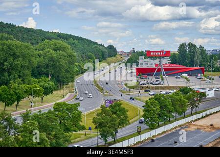 Panoramablick auf eine mehrspurige Autobahn mit moderatem Verkehr, der durch ein üppiges, grünes Stadtgebiet fließt. Auf der rechten Seite steht ein hervorstehendes Rot Stockfoto