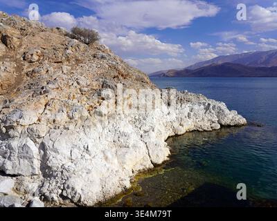 Weiße Kalksteinklippen und zerklüftete Felsformationen säumen die Küste von Akdamar Island und treffen unter einem hellen Licht auf das klare, tiefblaue Wasser des Lake Van Stockfoto