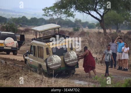 Ein Maasai-Mann hilft, ein Safari-Fahrzeug im Schlamm zu schieben, Tansania, Ostafrika Stockfoto