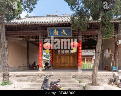 Luoyang, China - 5. Juni 2024: Traditionelles hölzernes Konfuzianisches Tempelgebäude mit roten Laternen, die von der Traufe hängen. Das Bild zeigt die lokale Bevölkerung Stockfoto