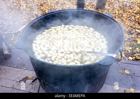 Teigtaschen mit Fleisch, gekocht in einem großen Kessel draußen Stockfoto