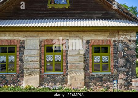 Nahaufnahme einer traditionellen litauischen Landhausfassade mit gemischtem Mauerwerk mit unregelmäßigen Feldsteinen und rotem Backsteinfenster Stockfoto