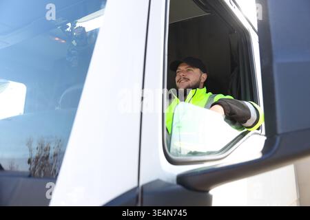 Glücklicher junger Fahrer, der in einem modernen Truck sitzt Stockfoto
