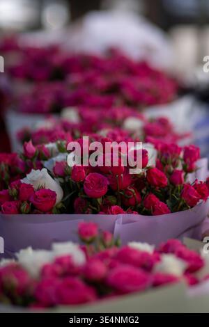 Ein lebendiges Schauspiel von rosa und weißen Rosen in eleganten Sträußen zum Verkauf auf einem Markt Stockfoto