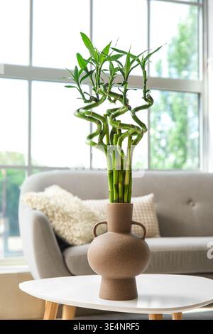 Vase mit grünen Bambusstielen auf dem Tisch in der Nähe des Fensters Stockfoto