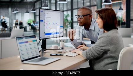 Junger Afrikanischer Mann Und Frau, Die Die Payroll App Auf Laptop Für Mitarbeiterzahlungen Verwenden. Büroassistent Stockfoto