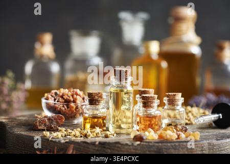 Auswahl ätherischer Öle in Glasflaschen mit Weihrauch, Myrrhe und getrockneten Kräutern Stockfoto