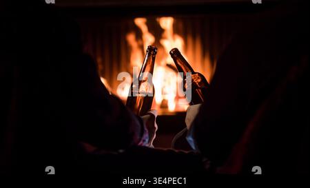 Winterurlaub - Männer entspannen sich am Kamin mit Bier in der Hand Stockfoto