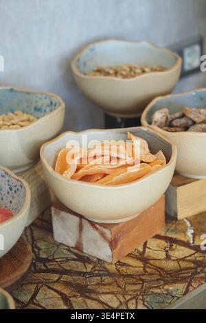 Getrocknete Früchte und Nüsse in Keramikschalen auf einem Tisch Stockfoto