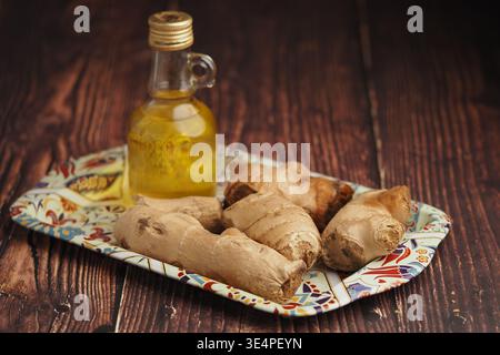 Ingwerwurzel und Öl auf einem farbenfrohen Gericht in einer Küche Stockfoto
