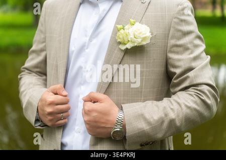 Boutonniere des Bräutigams mit weißer Calla-Blüte auf dem Revers des Anzugs. Stockfoto