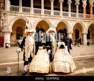 Venedig, Italien - 10. Februar 2026: Aufwendig gekleidete Figuren mit Masken stehen während der Karnevalsfeste von Venedig vor historischen Bögen Stockfoto