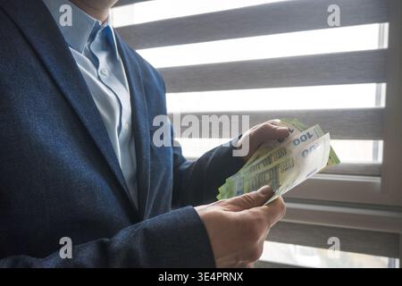 Mann im Anzug, der Euro-Banknoten hält, Geschäft. Stockfoto