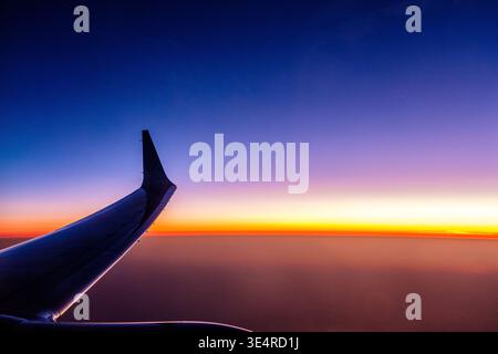 Der Blick von einem Flugzeugfenster auf den Sonnenuntergang während eines Fluges Stockfoto