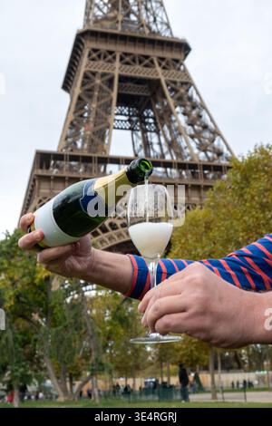 Ausgießen und Trinken von französischem Sekt aus Tulpenglas mit Blick auf die Straßen, Gebäude und Türme von Paris, Hochzeitsveranstaltung in Paris Stockfoto