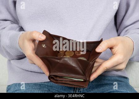 Eine Frau, die eine offene Ledertasche mit verschiedenen Euro-Münzen hält. Stockfoto
