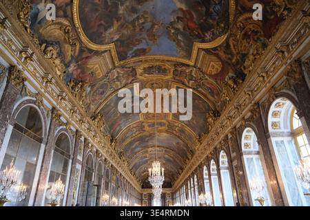 Paris, Frankreich-4. Oktober 2025: Kunstvolle Deckengemälde, Kronleuchter und Spiegelgalerie im Spiegelsaal im Schloss Versailles Stockfoto