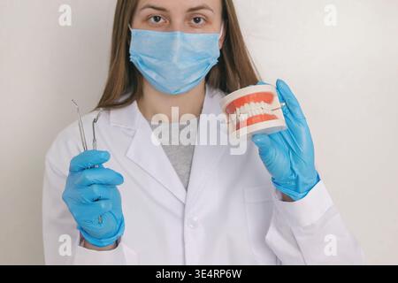 Zahnarzt im anatomischen Kiefermodell mit Maskenhalter und professionellen zahnärztlichen Werkzeugen Stockfoto