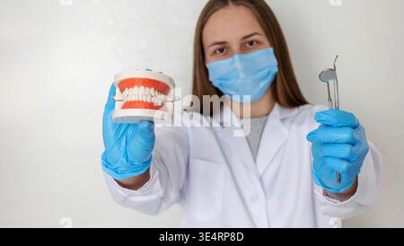Zahnarzt im anatomischen Kiefermodell mit Maskenhalter und professionellen zahnärztlichen Werkzeugen Stockfoto
