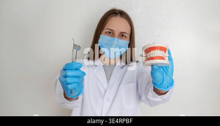 Zahnarzt im anatomischen Kiefermodell mit Maskenhalter und professionellen zahnärztlichen Werkzeugen Stockfoto