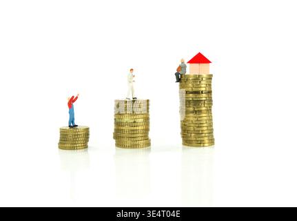 Miniaturmenschen Auf Münzstapeln Mit Hausmodell, Das Vermögen, Ersparnisse Und Immobilienungleichheit Repräsentiert Stockfoto