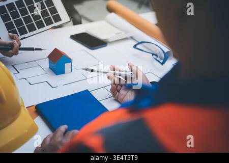 Ein Ingenieur und ein Architekt prüfen gemeinsam Baupläne und Baupläne auf einer belebten Baustelle Stockfoto