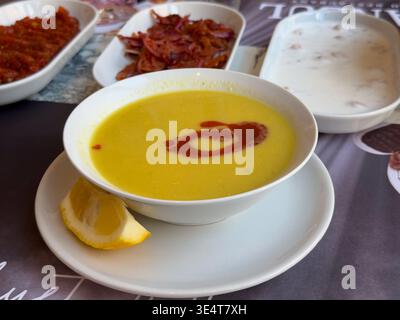 Cremige Linsensuppe, serviert mit Paprikaputter, Swirl und Zitrone auf einem weißen Teller. Traditionelles türkisches Komfortessen, Vorspeisenpräsentation im Restaurant und Stockfoto