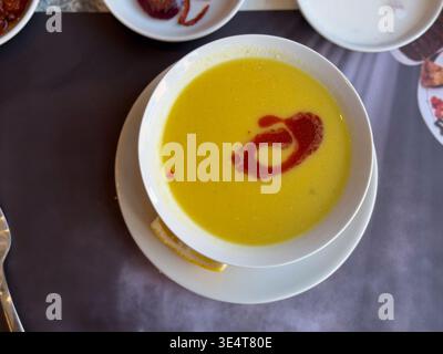 Cremige Linsensuppe, serviert mit Paprikaputter, Swirl und Zitrone auf einem weißen Teller. Traditionelles türkisches Komfortessen, Vorspeisenpräsentation im Restaurant und Stockfoto