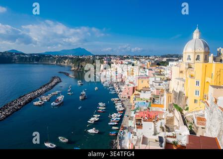 Blick auf die farbenfrohen Häuser und Boote im Hafen von Marina Corricella auf der Insel Procida, Italien, mit dem Santuario di Santa Maria delle Stockfoto